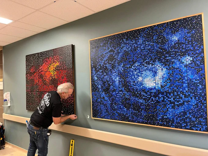 ArtWorks for Cancer team member Don Tannahill's logistics and installation skills ensure every painting is beautifully and safely displayed in every hospital setting. Here, Don installs Veronica K. Fierke's Laguna Nebula, 2022 and Eagle Nebula, 2013 in the Inpatient Oncology/Palliative Care Unit of Brampton Civic Hospital.