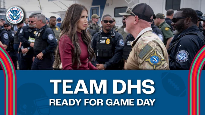 Secretary Kristi Noem shakes hands with a DHS staffer at a 'Team DHS Ready for Game Day' event, with other uniformed security personnel around them.