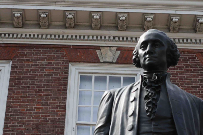 Bronze statue of George Washington with a brick building in background. 
