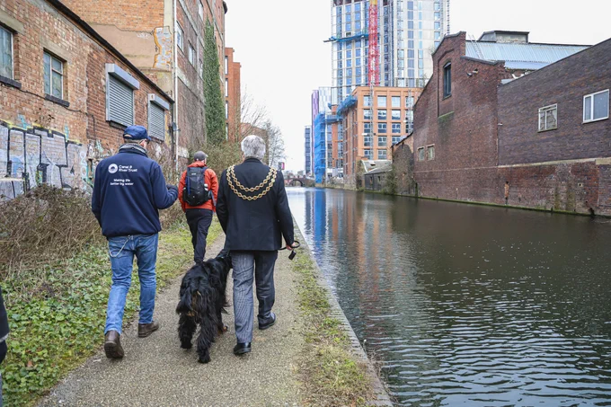 The Lord Mayor of Birmingham walks alongside a large canal in Birmingham.
