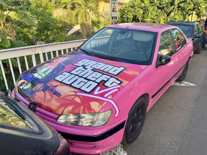 Pink tuned Peugeot car with a GTA VI art hand painted on the hood, parked in Sainte Anne, Martinique, during the 2025 carnaval.