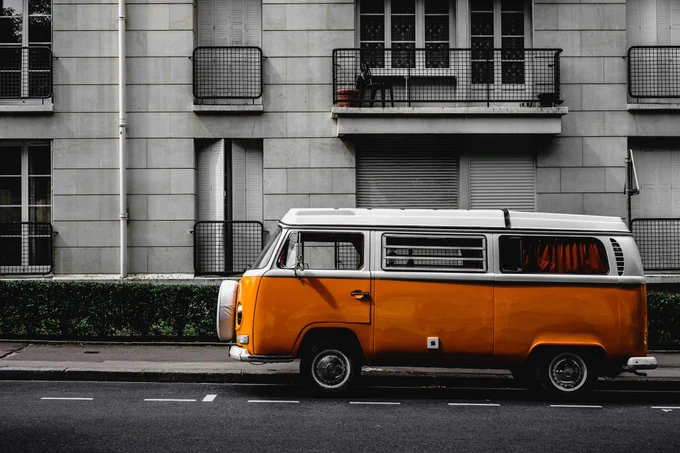 a photograph of an orange camper van parked in a city street