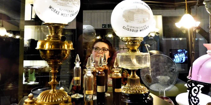 Museum visitor looking at a display of old oil lamps
