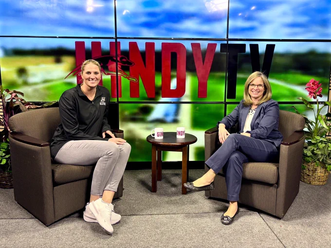 Haley Kindall (left) & Kim Pate (right) sit in the UIndy TV studio chairs, smiling for the camera prior to their interviews on Good Morning Greyhounds.