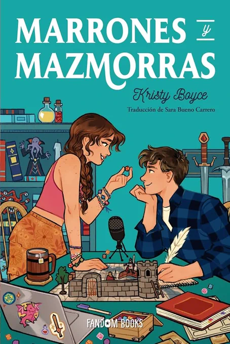 Cubierta de Marrones y mazmorras (Dating and Dragons) de Kristy Boyce, publicado en España por Fandom Books, traducido por Sara Bueno Carrero. Una chica con frienship bracelets y un d2 entre los dedos mira a un chico sentado frente a ella. Ambos comparten una sonrisa desafiante. Sobre la mesa hay un micro direccional, un portátil decorado con pegatinas de fantasía, cajas de dados, material de rol y una ambientación a escala de un castillo con algunos personajes sobre una cuadrícula. A espaldas de los personajes hay una estantería con gruesos libros y estatuillas de monstruos como el mind flayer.