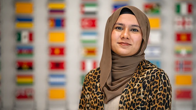 A student with the wall of flags behind them