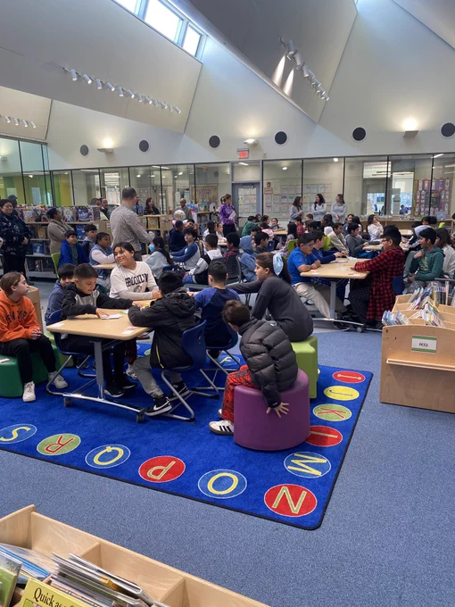 Library filled with teams of eight students around a table