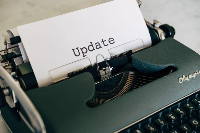 a photograph of an old fashioned manual typewriter. There is a piece of paper in it with the word 'update' typed on it