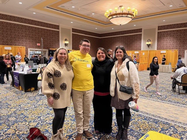 male student in yellow shirt standing with 3 female adults