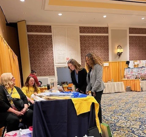 two adults talking to a student and teacher; wearing yellow shirt