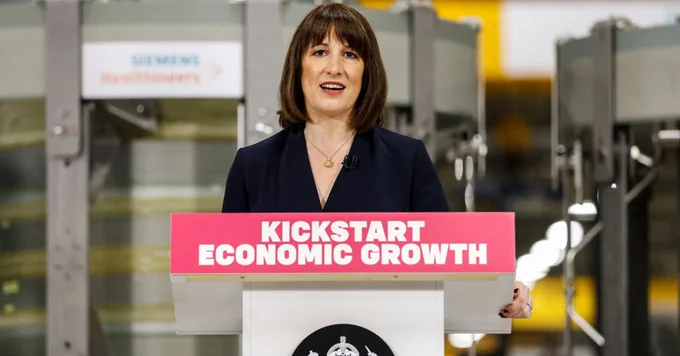 Photo of Rachel Reeves standing at a podium that reads 'Kickstart Economic Growth'.