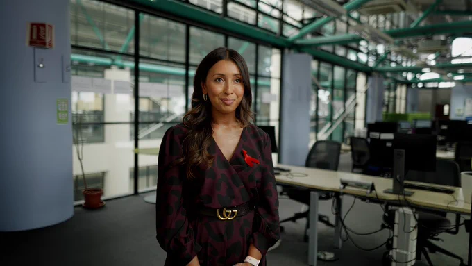 A woman, Dr Ruby Uddin, a GP from Kingston is standing in a room
