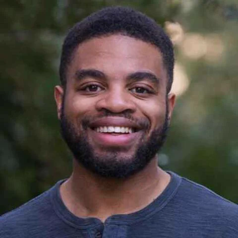photo of Maurice Rippel, smiling at the camera with greenery in the background