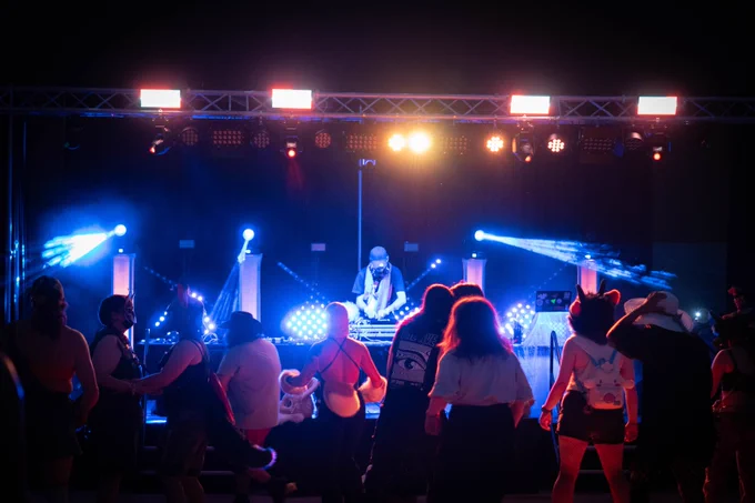 DJ performing on stage in front of dancing crowd of furries at Eufuria.