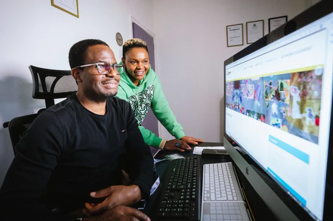 Two adults smiling and looking at a computer screen.