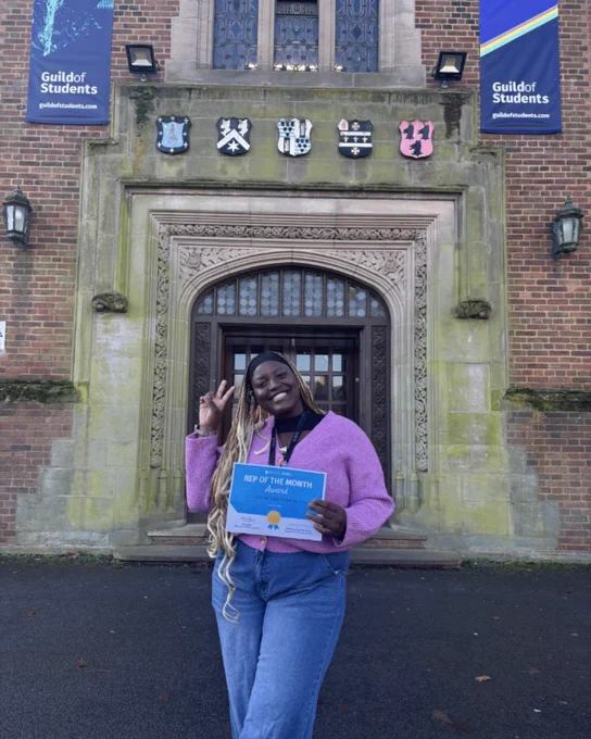 Image of a student smiling in front of the Guild building having won Rep of the Month for January.