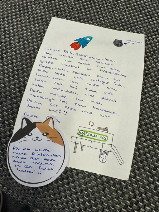 Auf einem Hand-geschriebenen Zettel bedankt sich eine Schülerpraktikantin für die Zeit bei uns im DLR, die ihr ganz viel Spaß gemacht hat und sie viele neue Dinge lernen konnte. Dabei hat sie auch schöne kleine Bilder gemalt: eine Rakete, einen kleinen Mond und das Labor EDEN ISS.