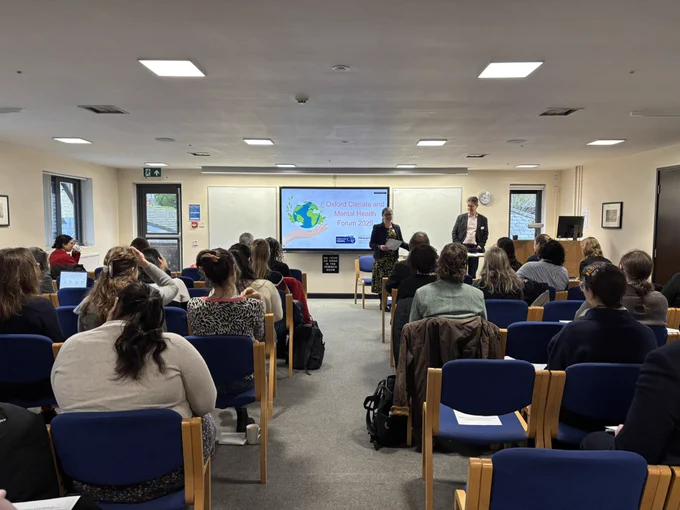 A room full of people, a screen that says “Oxford Climate and Mental Health Forum”