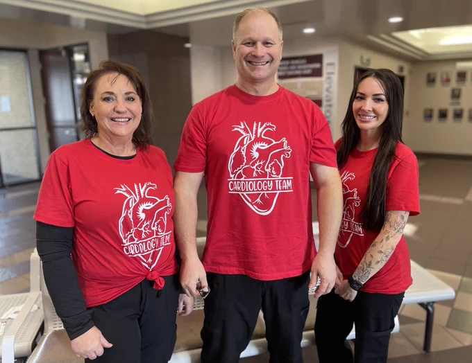Three members of the Cath Lab team at MountainStar Healthcare’s Mountain View Hospital in Payson, Utah, pose together as a group, smiling, outside the Utah County Commission Chambers.