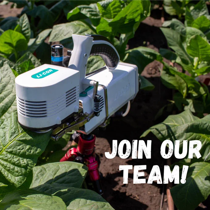 A small, white machine takes a measurement of a green leaf surrounded by other leaves. White text in the bottom right says Join Our Team!