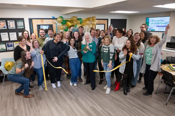 A group of people celebrate at a ribbon cutting