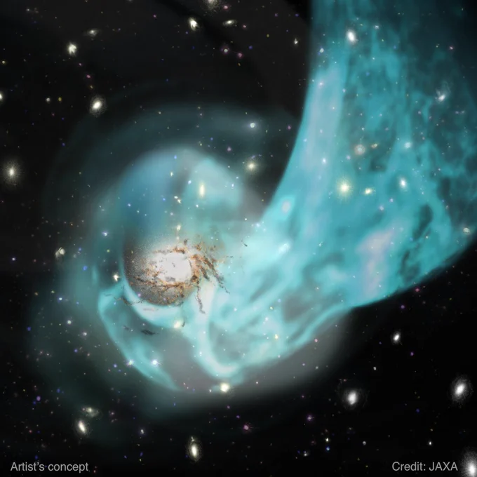 This illustration depicts the center of the Centaurus cluster based on data from XRISM and other observatories. The black backdrop features dozens of round and oval spots in shades of yellow, red, and blue, representing the galaxies in the cluster. Just to the left of center is a large bright oval surrounded by tendrils of tan and dark brown like a small firework. A cloud of patchy electric blue representing the hot gas encircles the bright oval and swings up to the right, like a scarf flung around someone’s neck. The image is watermarked “Artist’s concept” and “Credit: JAXA.”