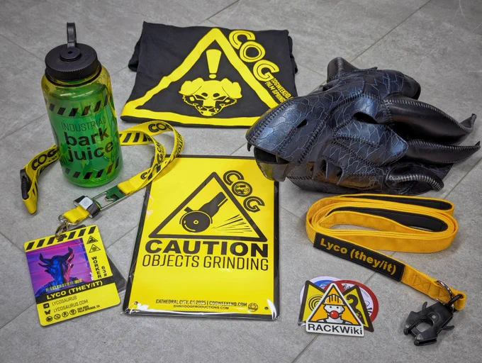My swag from COG Weekend 2025 by Shiny Dog Productions: Soft ringspun screenprinted T-shirt, Nalgene® water bottle, embossed metal sign, vinyl stickers, lanyard with release buckle & bottle opener, plastic personalized photo ID event badge, & personalized embroidered name patch attached to a long/short combo leash featuring a quick connect latch & neoprene handles... talk about QUALITY