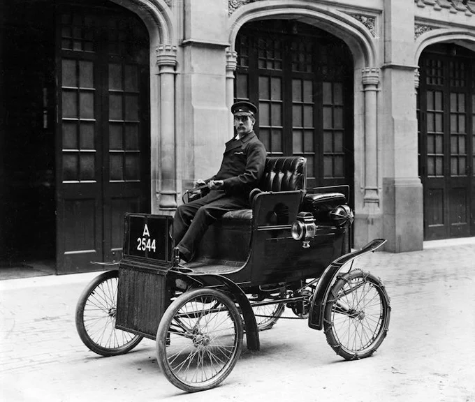 Metropolitan Fire Brigade firefighter Samuel Egerton, posed outside a fire station on an early motorised car. Photograph taken in around 1904