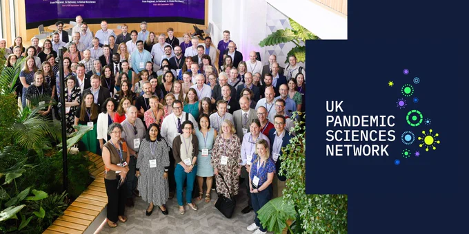 A large group of people gathered for an event, representing the UK Pandemic Sciences Network. The right side features the network's logo, with colourful virus-inspired designs.