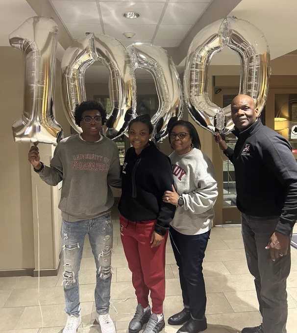 Elana and her family pose with balloons that have the numbers 1000.