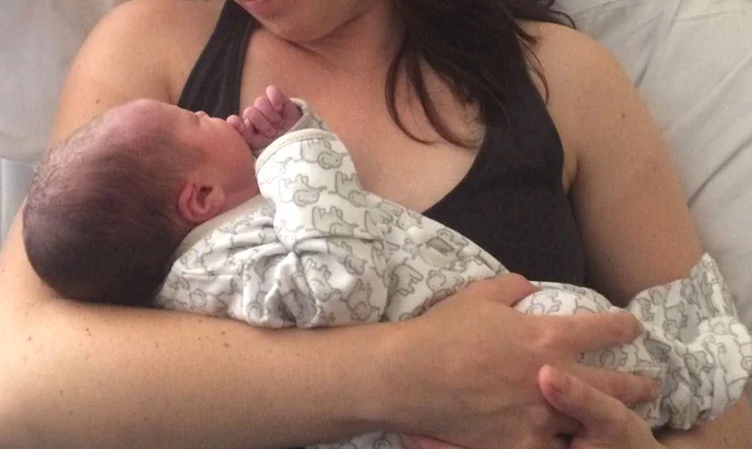 Woman's arms cradling newborn.