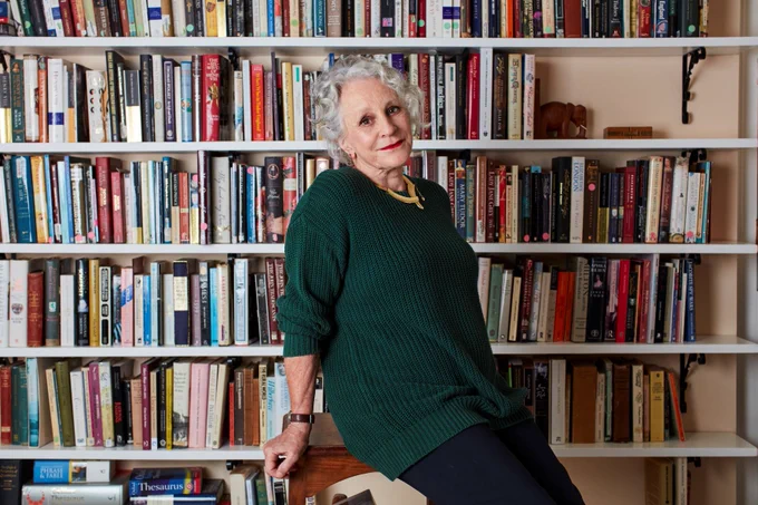 This is a photograph of author Philippa Gregory looking at the camera and sitting in front of book shelves.