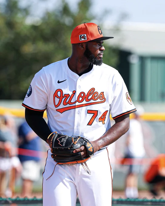 Félix Bautista throws from the mound during a bullpen session at Spring Training. He is wearing a white Orioles uniform. His glove says "The Mountain" with the No. 44 on it. 