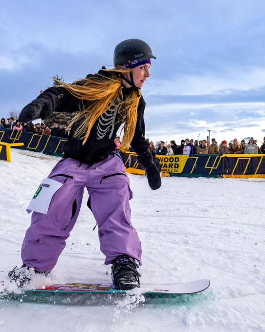 A snowboarder snowboarding down a hill.