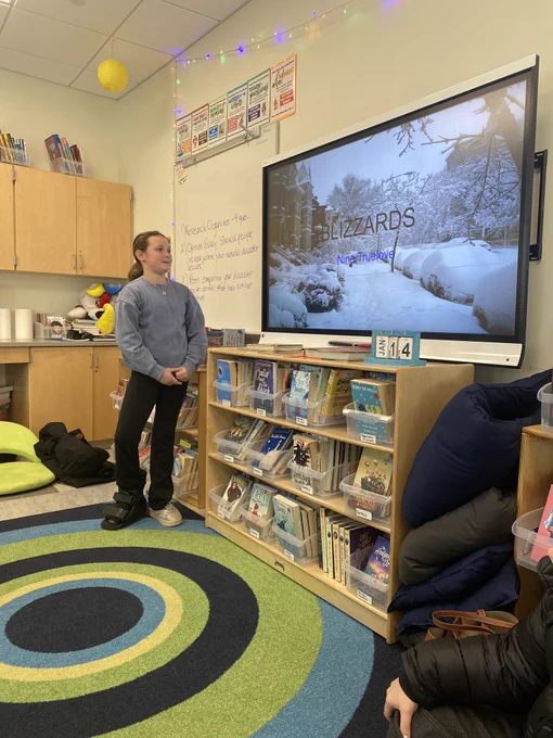 Student stands in front of smart bird with presentation titled blizzards