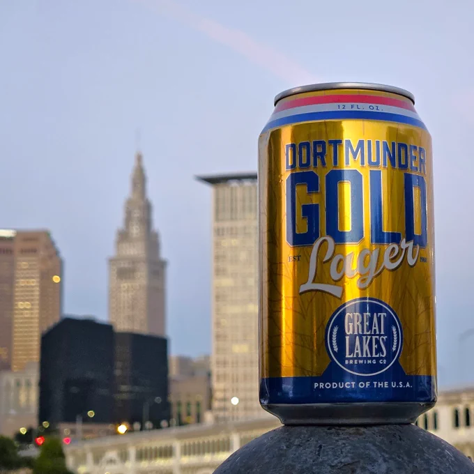 Dortmunder Gold Lager in front of the Cleveland skyline at dusk.