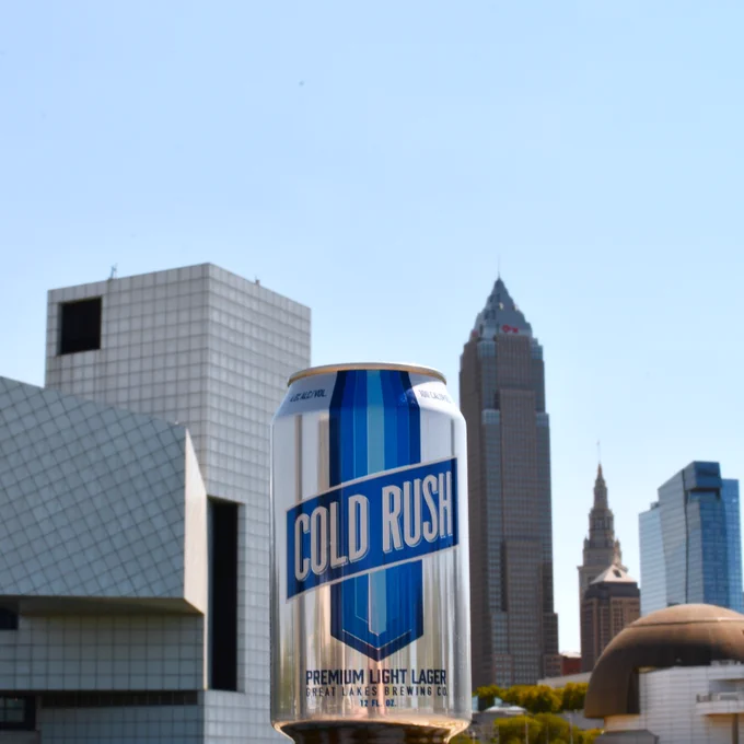 Cold Rush Premium Light Lager in front of a sunny Cleveland skyline.