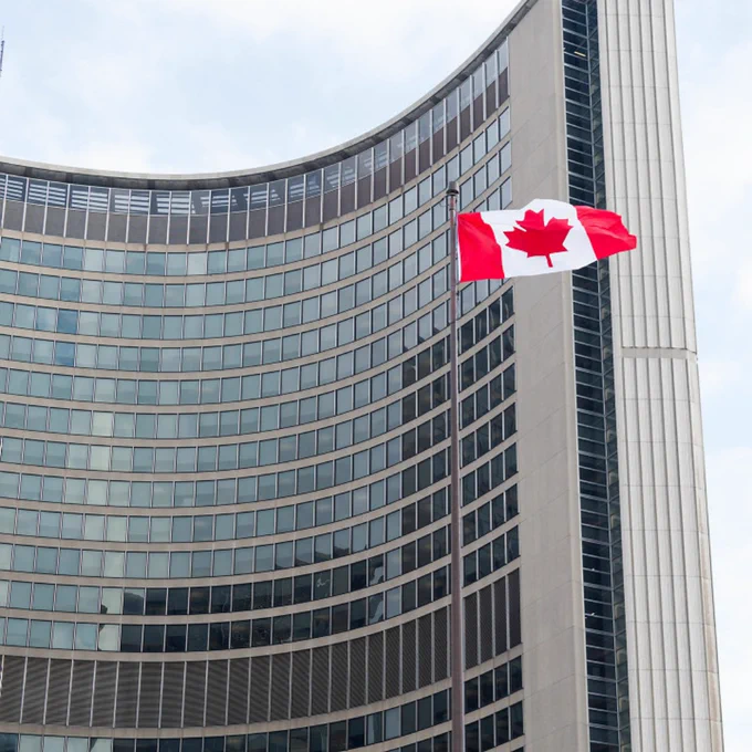 Canadian Flag fluttering in the wind with City Hall in the background.