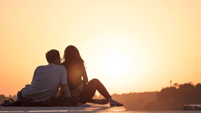 Photo of two teenagers sitting down looking off into the sunset. Credite StockSnap