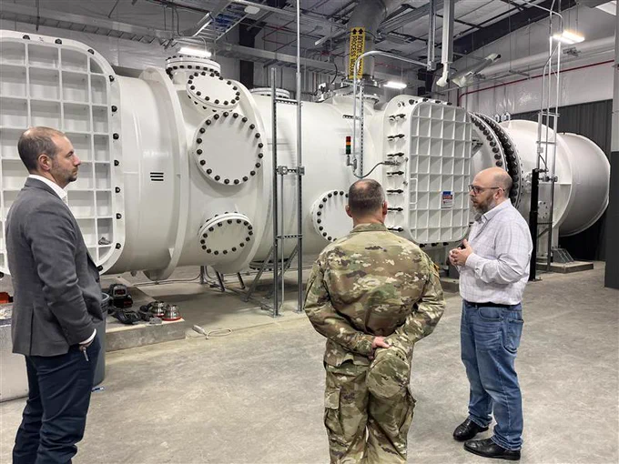 Three men standing in the Ballistic, Aero-optics and Materials range at Texas A&M-RELLIS.