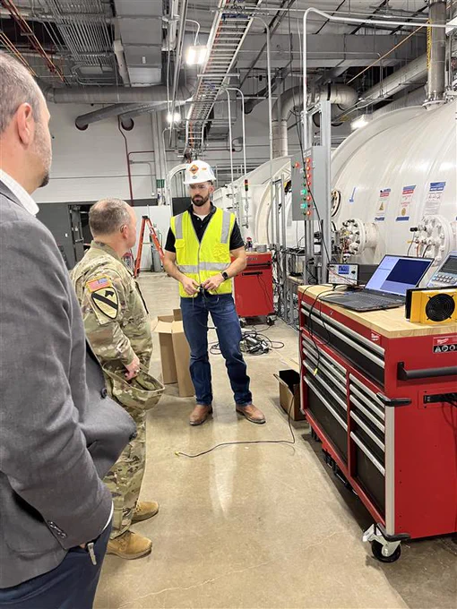 Three men standing in the Ballistic, Aero-optics and Materials range at Texas A&M-RELLIS.