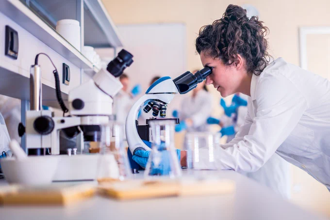 Lab scientist checks a sample under the microscope.