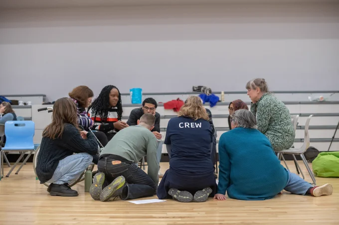 A small group sits on the ground and chairs to talk about one of the Assembly themes. 
