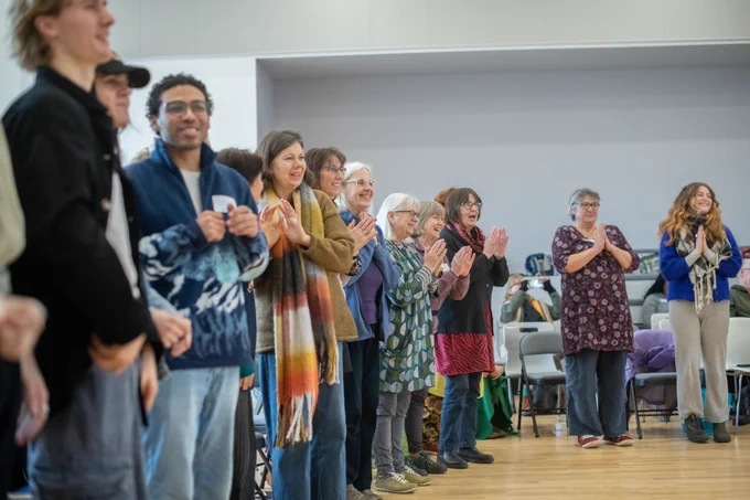 A group of Assembly participants of all ages stand in a curved line. 