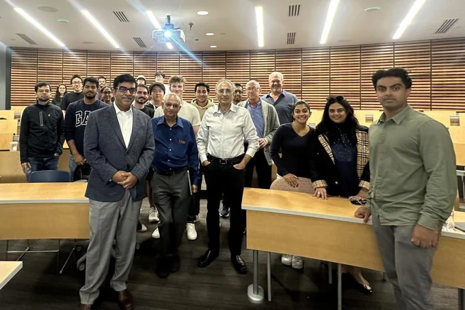 Group of people posing together in an auditorium with wooden paneling.
