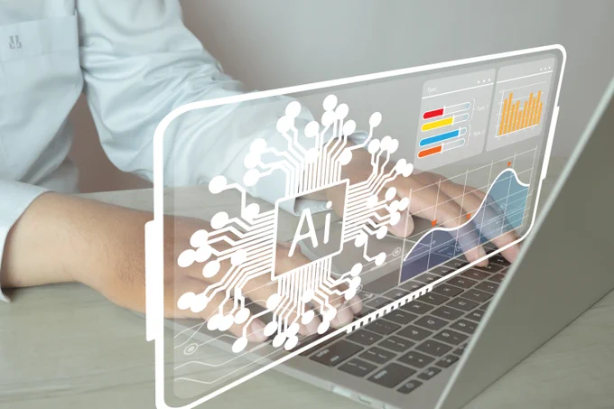 A person types on a laptop computer as a second screen emerges from the keyboard with charts and graphs and the abbreviation AI.