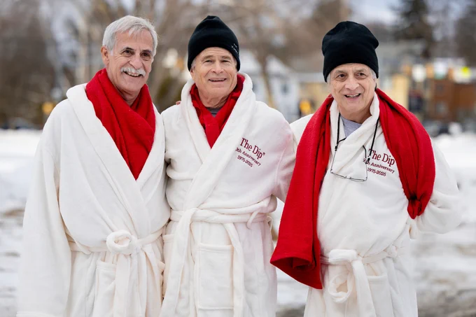 The three original puddle jumpers stand and smile in their white robes and bright red scarves before the 2025 Puddle Jump.