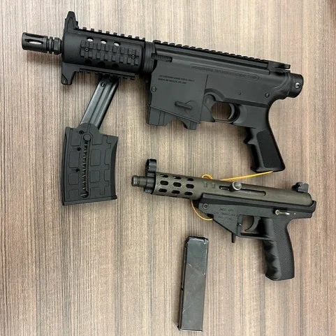 Two semiautomatic pistols displayed on a table. One is an AR-style 9 mm, the other a .22 caliber TEC-9 style. 