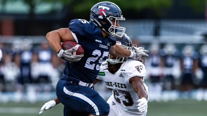Luka Stoikos carries the football as a defender tries to tackle him during a University of Toronto Varsity Blues football game against the University of Ottawa Gee-Gees