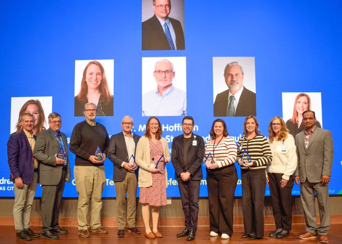 10 people stand side-by-side. Some are holding the awards they received. The others are those who presented them with the award or were involved in deciding who should receive the award. Children's Mercy CEO Alejandro Quiroga stands in the middle. 